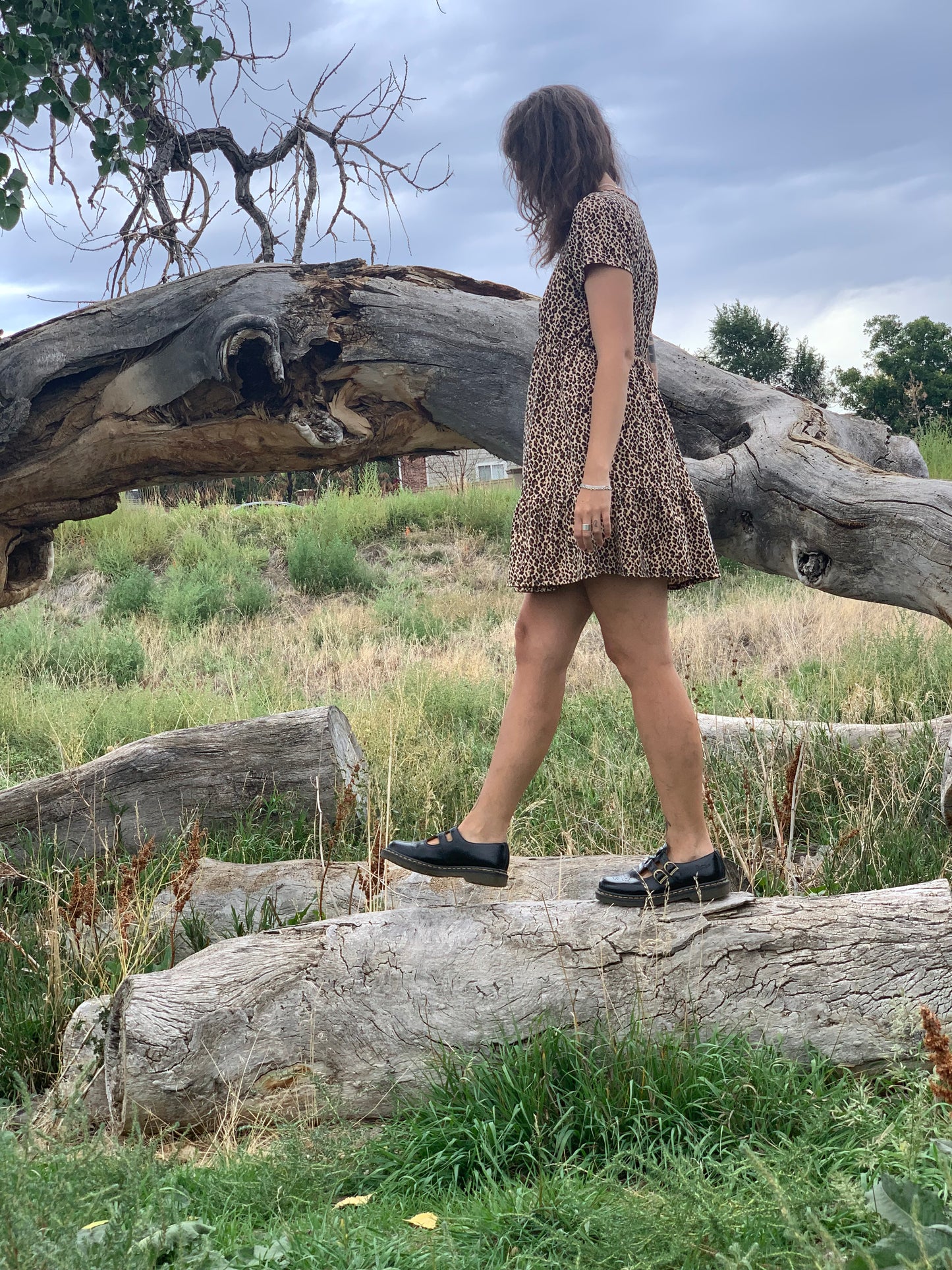 Person standing in a natural setting with large trees and grass.