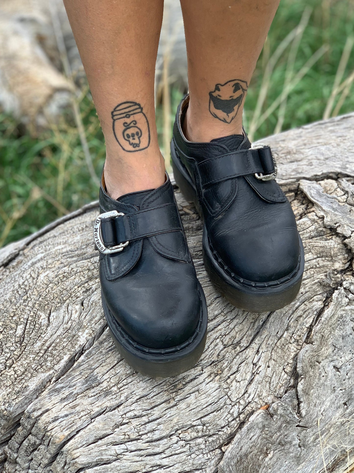 Black leather shoes with buckles on a wooden log
