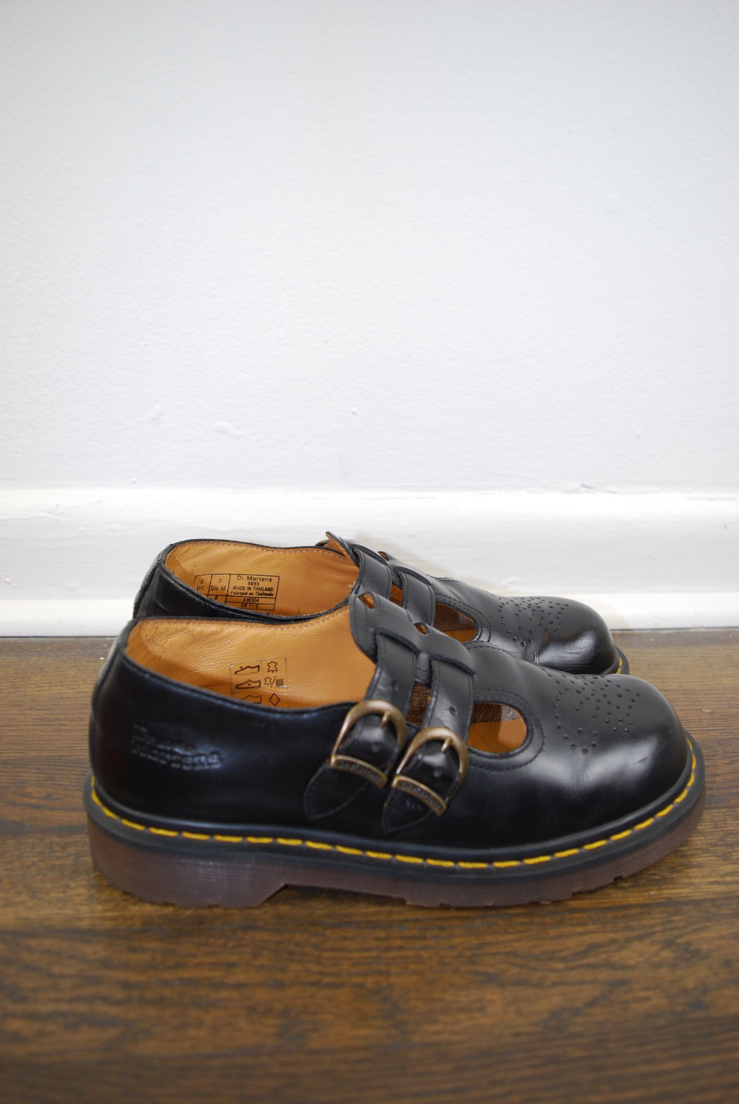 Black leather shoe with a brown sole on a wooden surface