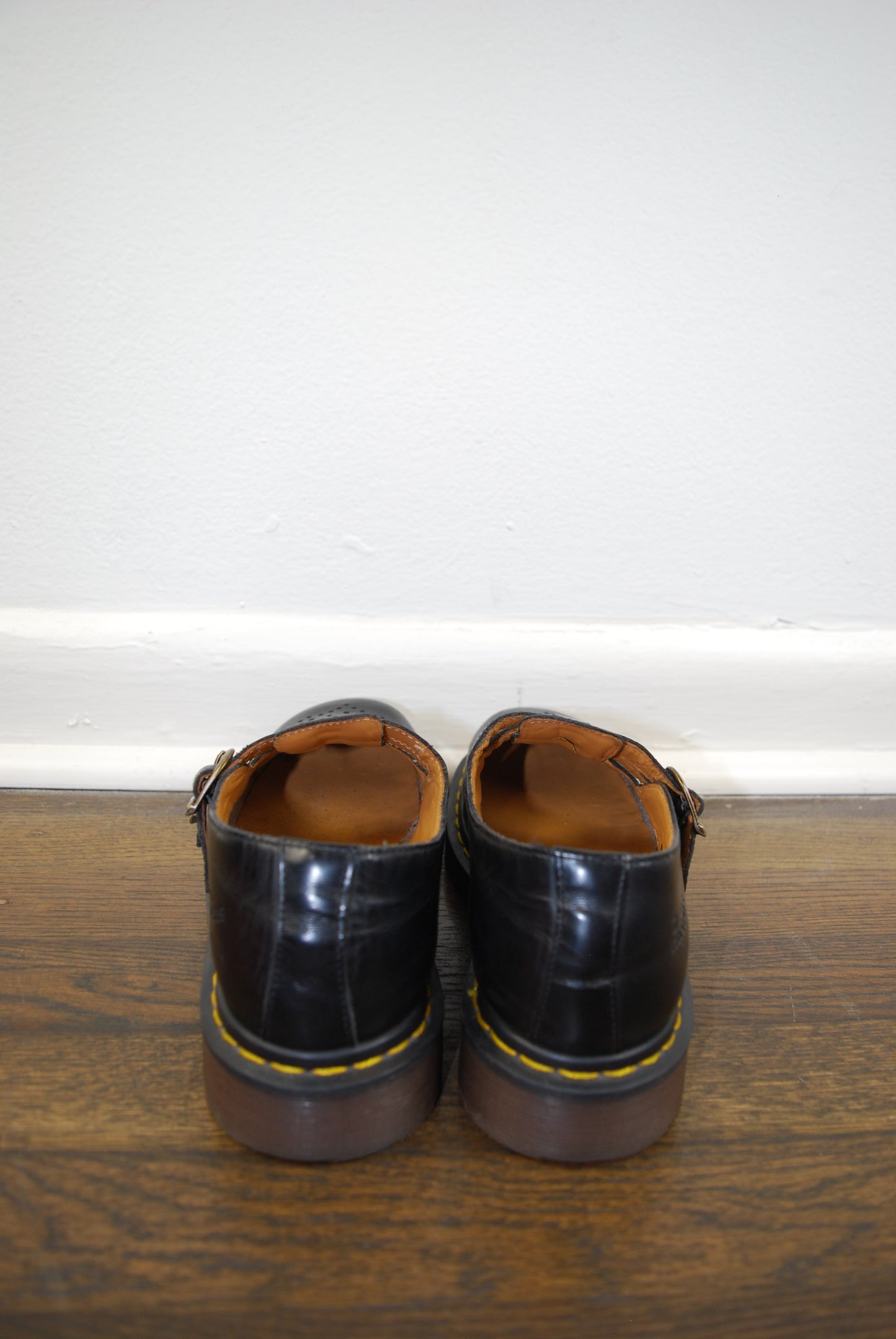 Pair of black leather shoes on a wooden surface with a white background