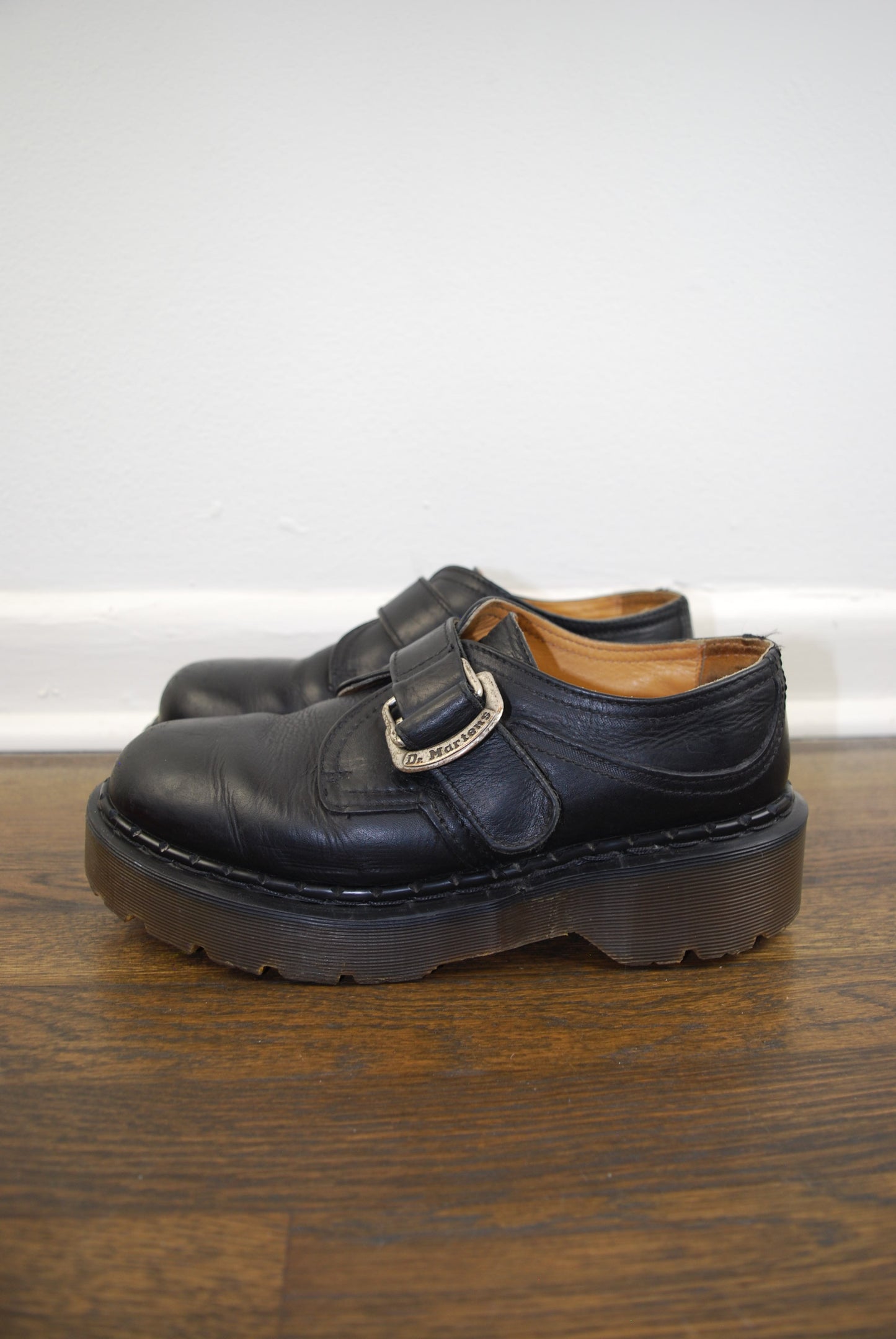 Black leather sandal with a strap on a wooden surface