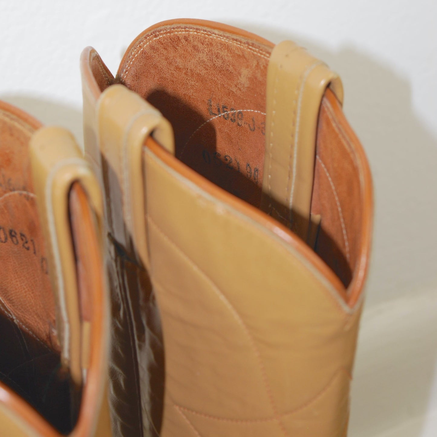 Close-up of a tan leather boot with visible stitching on a white background