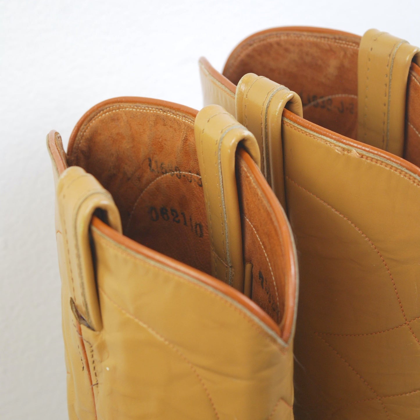 Pair of tan leather boots with visible wear on a white background