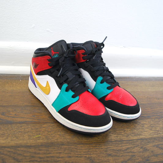 Colorful sneakers with a black base on a wooden floor.