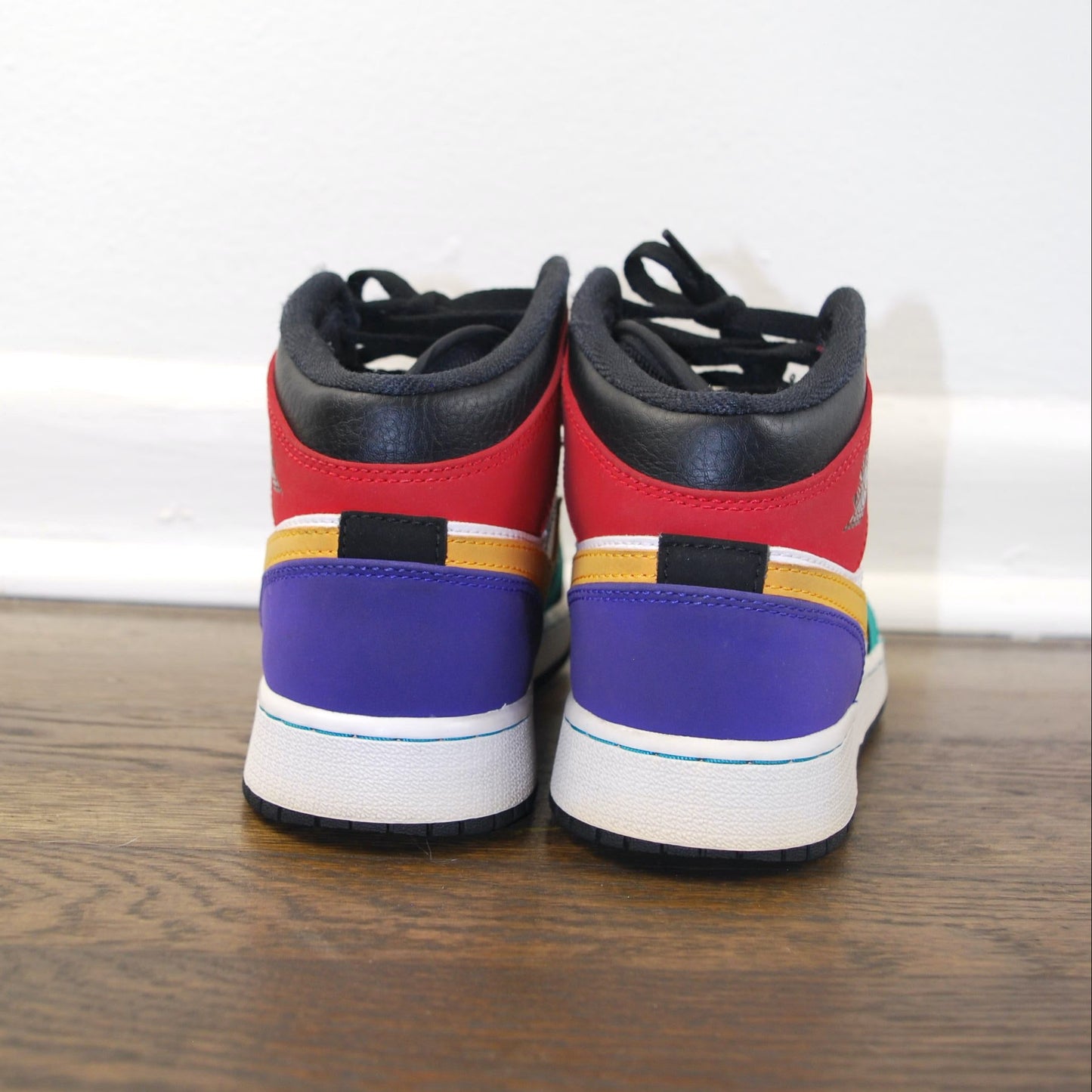 Colorful high-top sneakers on a wooden floor with a white wall background