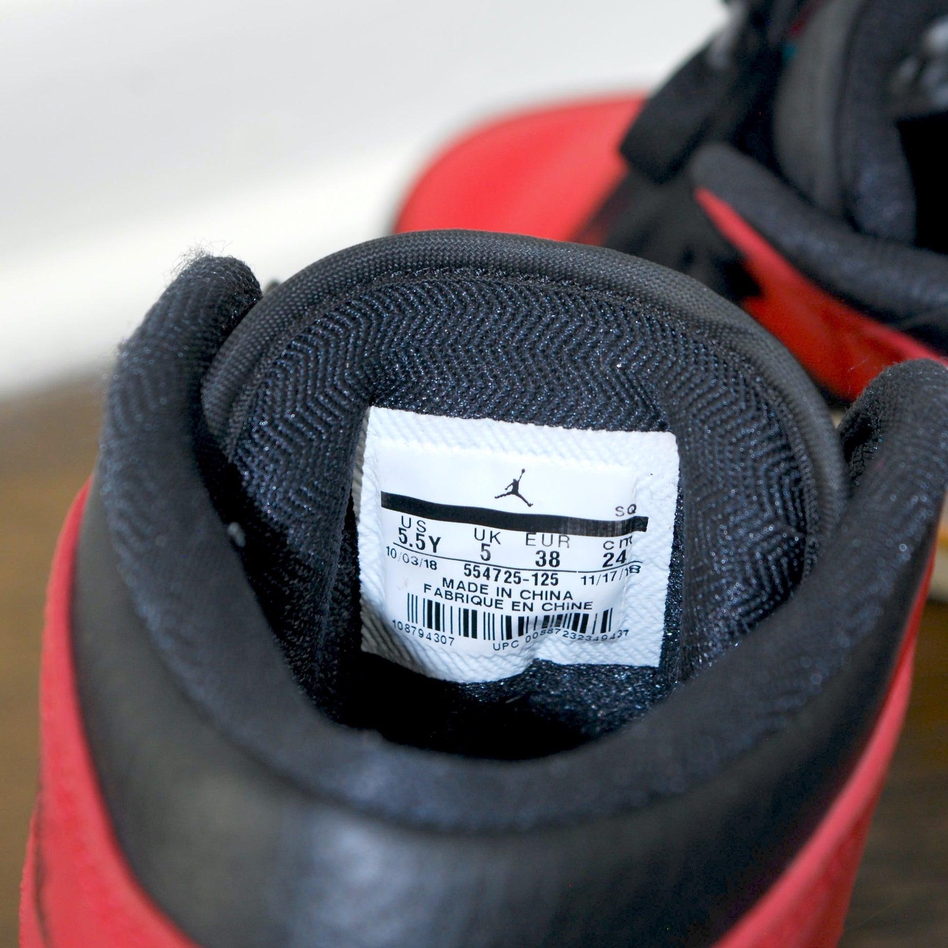 Close-up of a red and black sneaker with a brand label on a white background