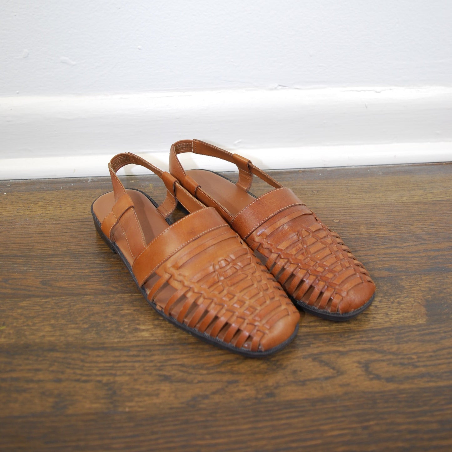 Pair of brown sandals on a wooden floor