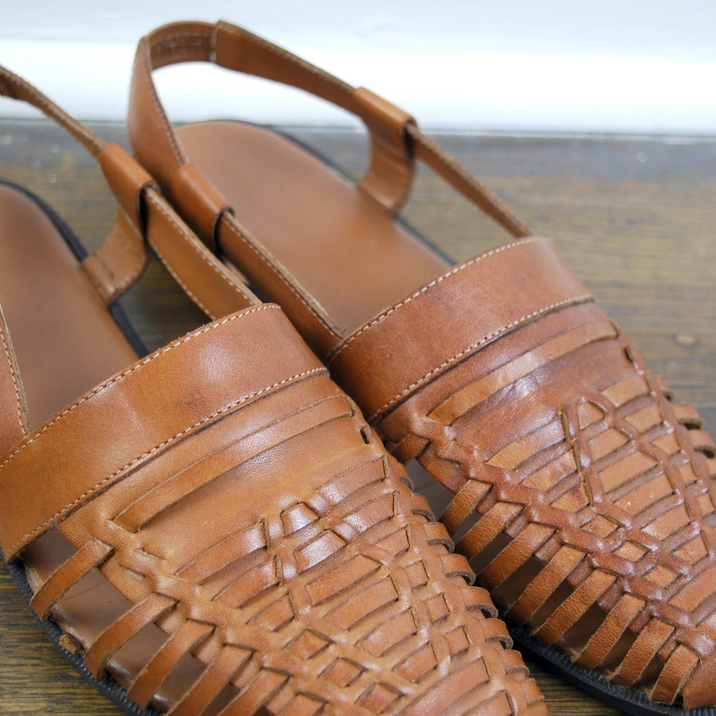 Pair of brown sandals with woven straps on a wooden surface