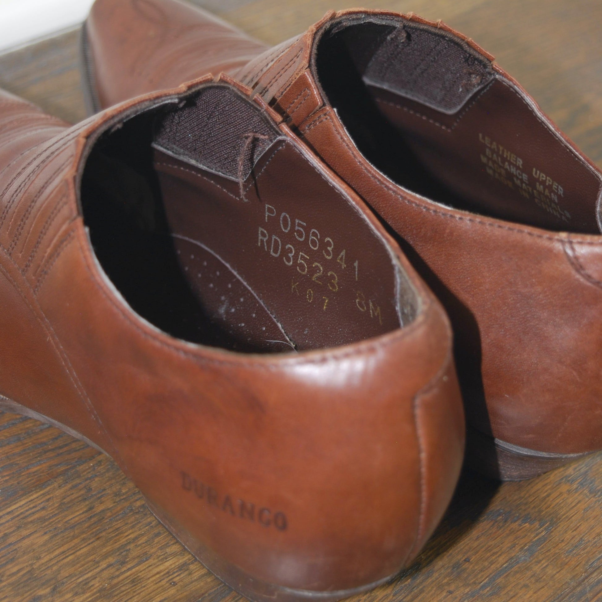 Pair of brown leather shoes on a wooden surface