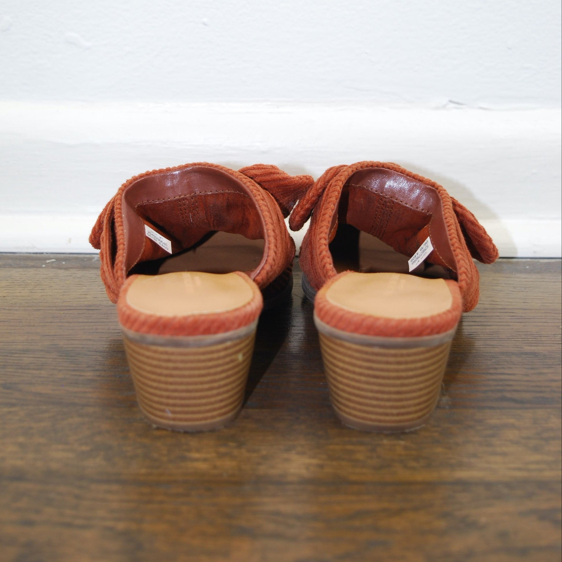 Pair of brown sandals with wooden soles on a wooden floor.