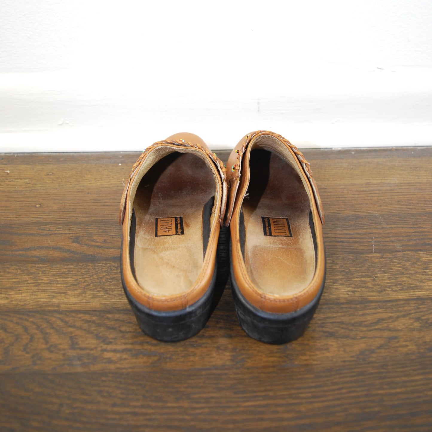 Pair of brown shoes on a wooden surface with a white background