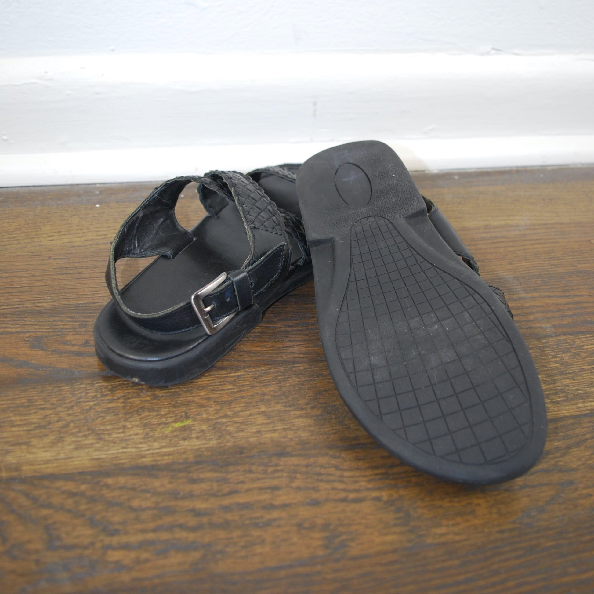 Black sandal with a strap on a wooden surface