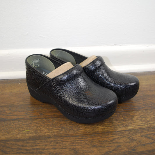 Black crocodile-patterned high-heeled shoes on a wooden floor.