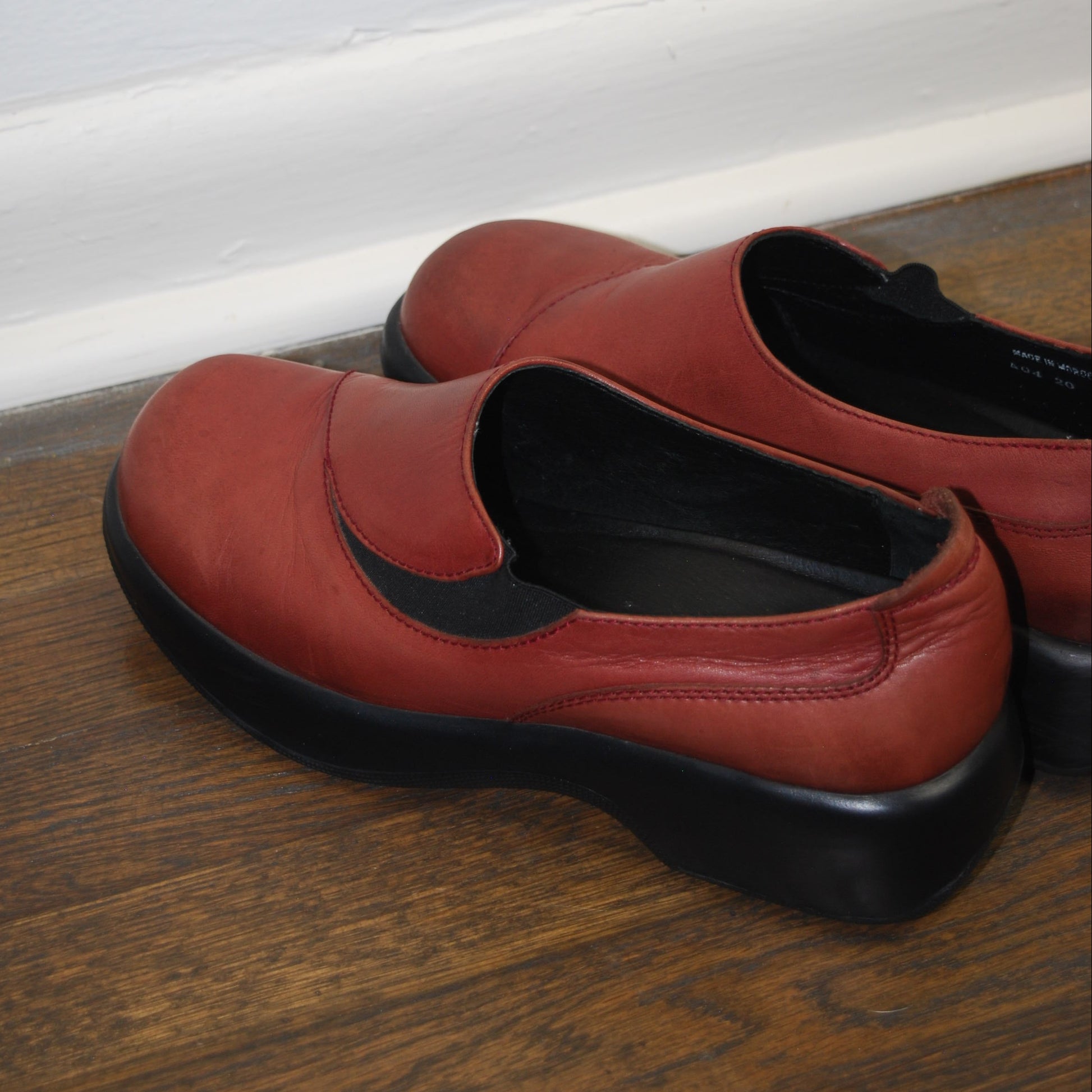 Brown shoe on a wooden floor with a white baseboard