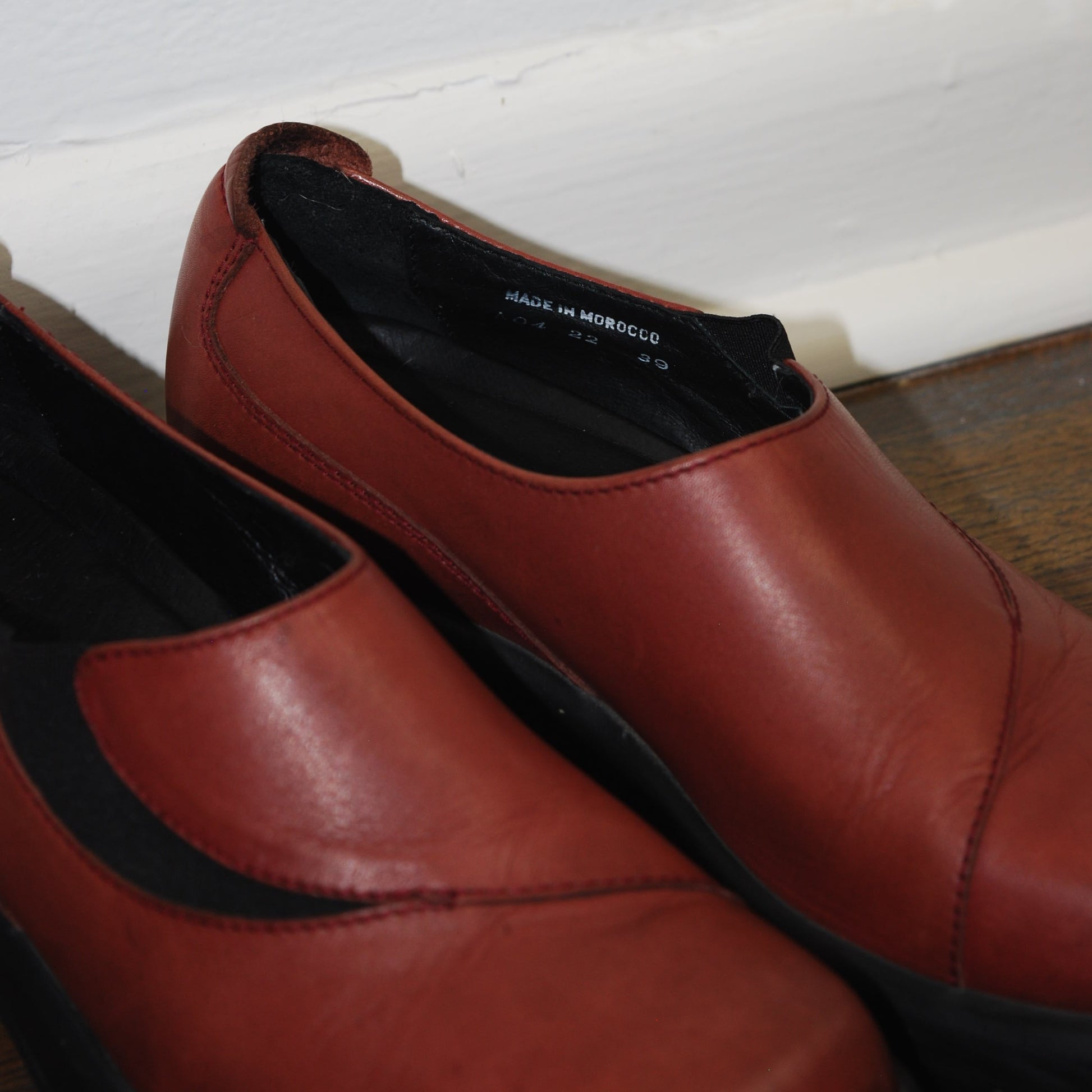 Brown leather shoes with black soles on a white background
