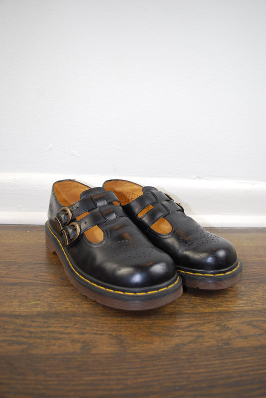 Black leather sandal with brown insole on a wooden surface