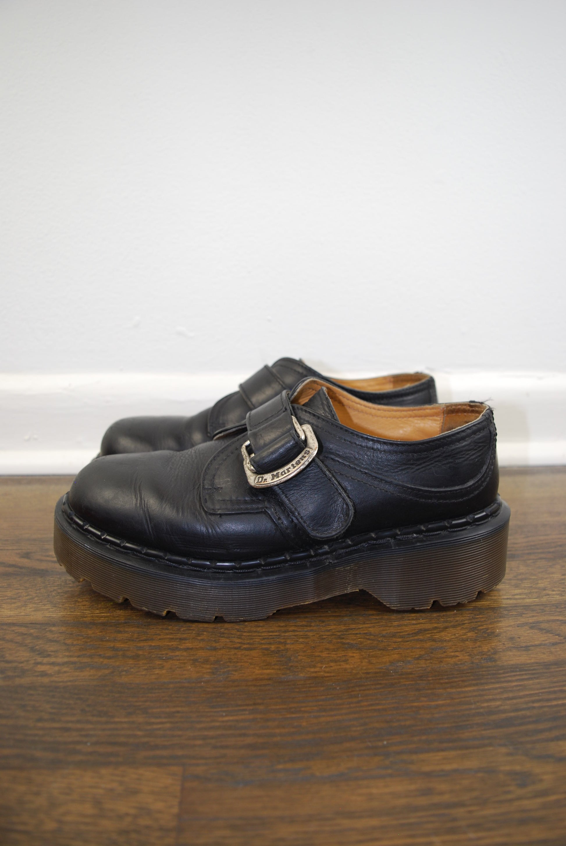 Black leather sandal with a strap on a wooden surface