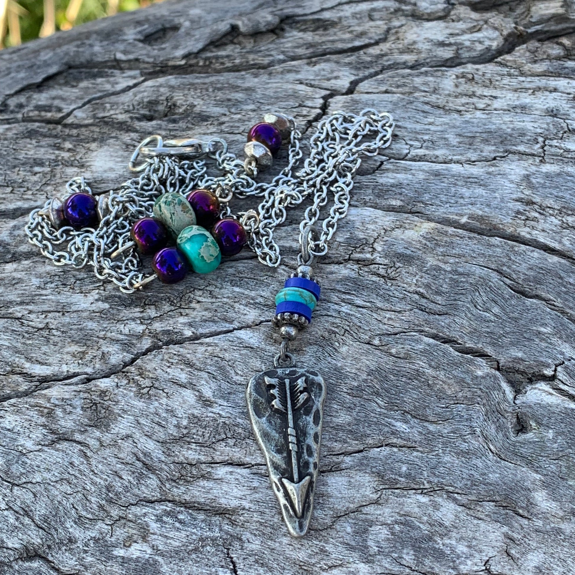 Necklace with arrowhead pendant on a textured stone surface