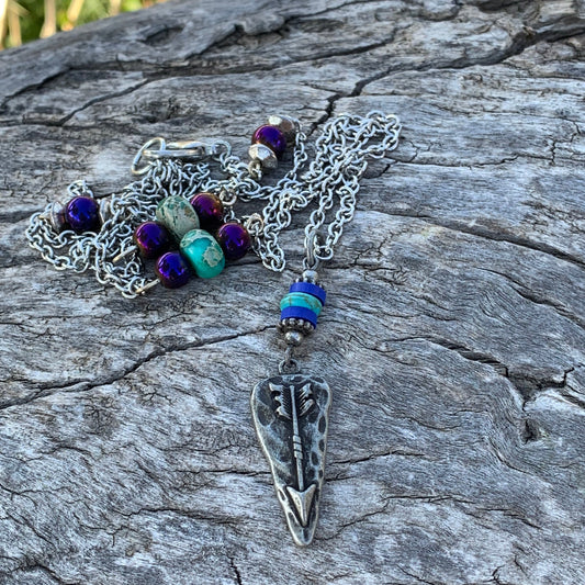 Necklace with arrowhead pendant on a textured stone surface