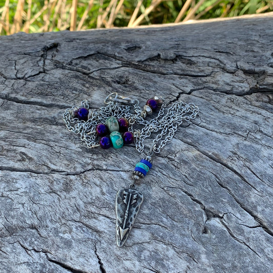 Necklace with blue and purple stones on a textured stone surface