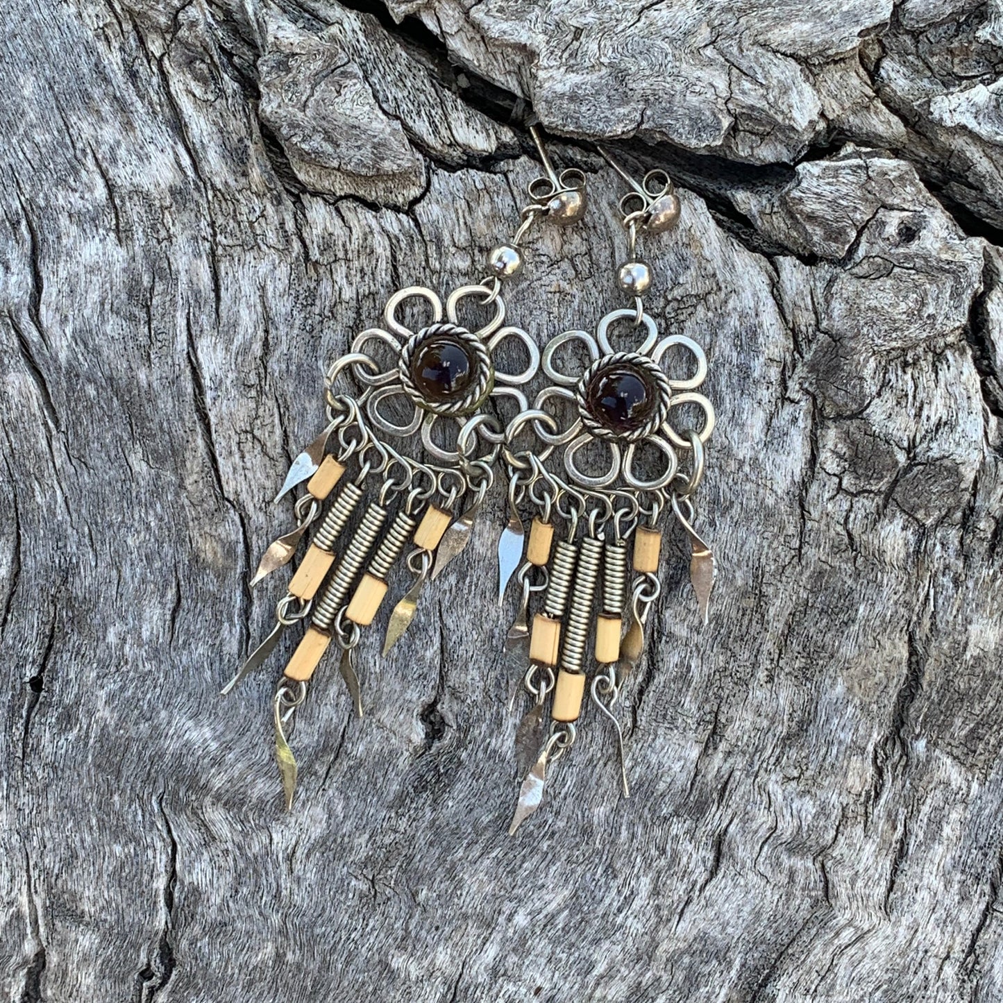 Decorative earrings with black stones on a textured stone surface