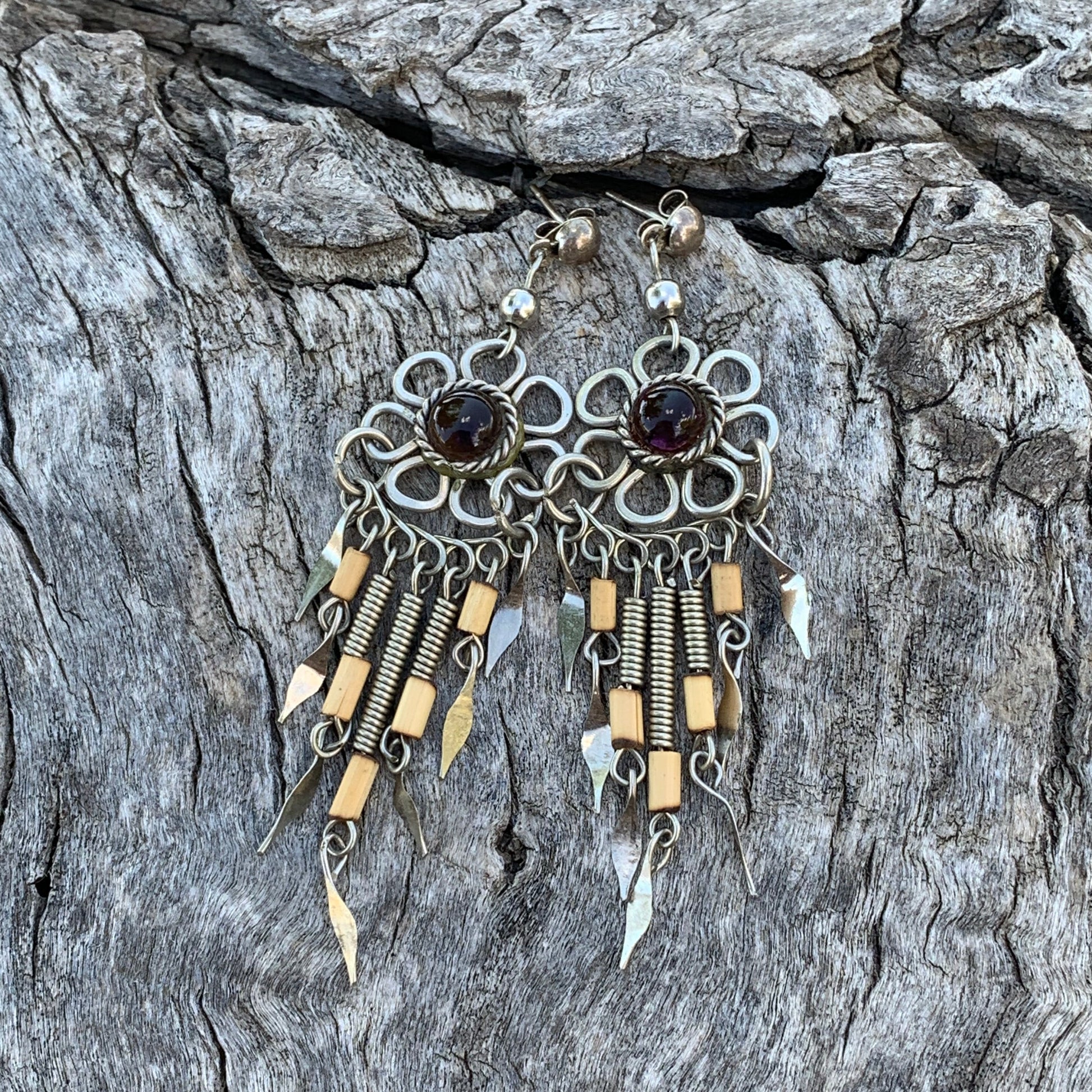 Pair of earrings with gold and silver design on a textured stone surface