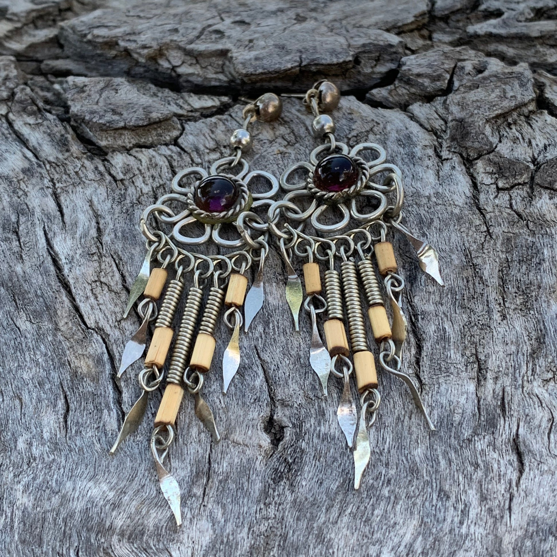 Pair of intricate earrings on a textured wooden surface