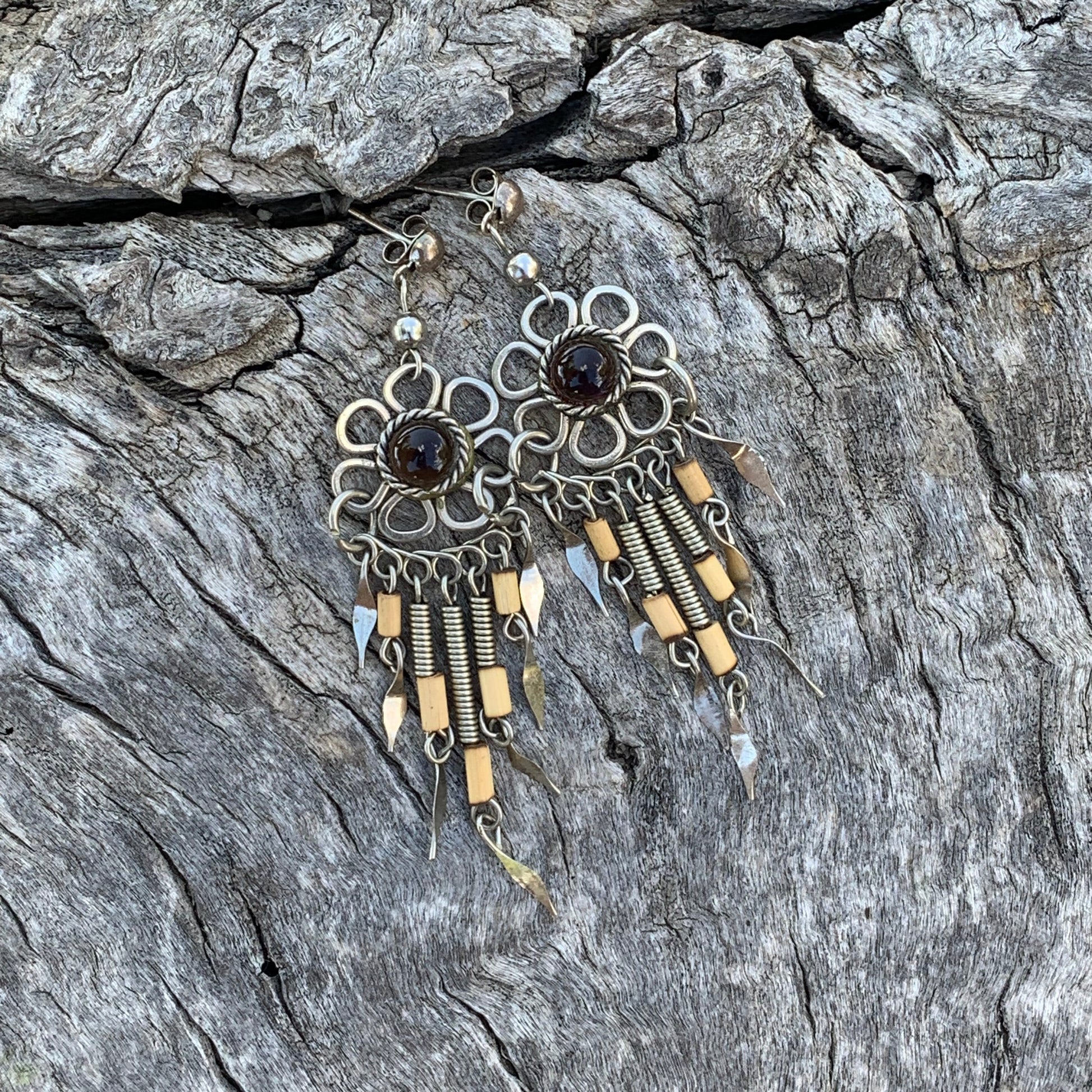 Pair of ornate earrings on a textured stone surface