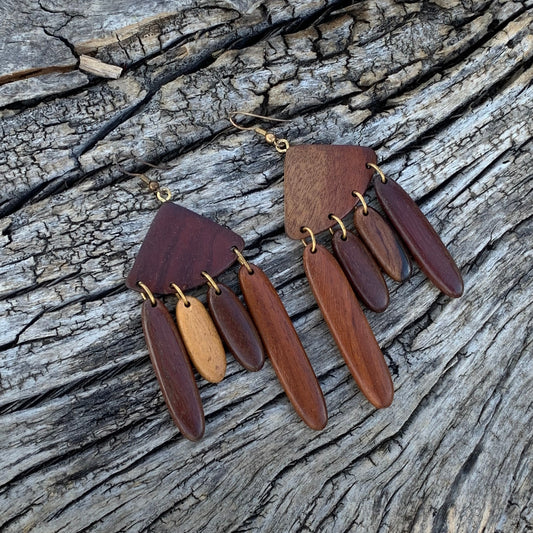 Wooden earrings with gold accents on a textured wooden surface