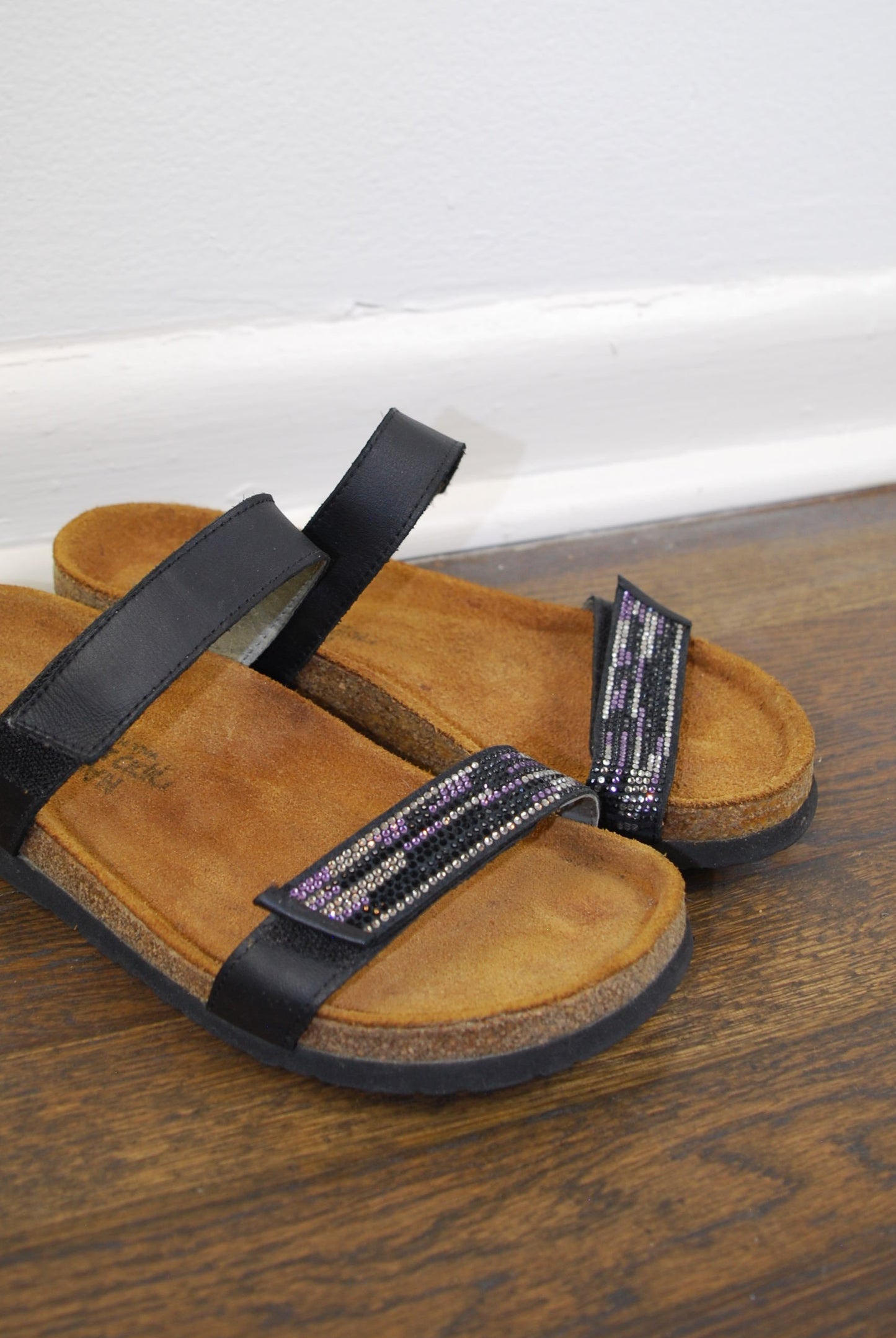Brown sandal with black straps on a wooden surface