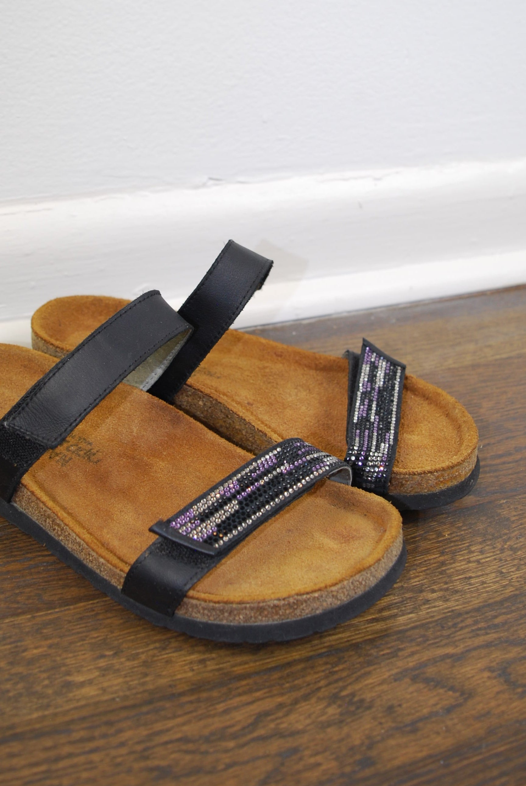 Brown sandal with black straps on a wooden surface