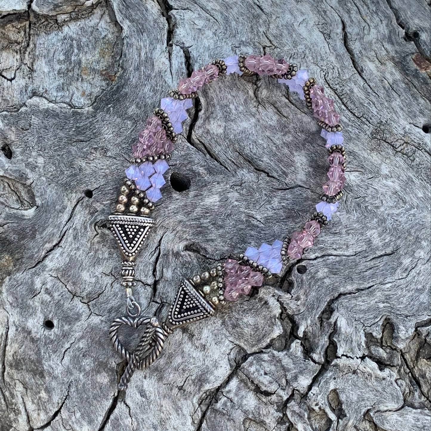 Decorative headband with pink and purple flowers on a textured stone surface