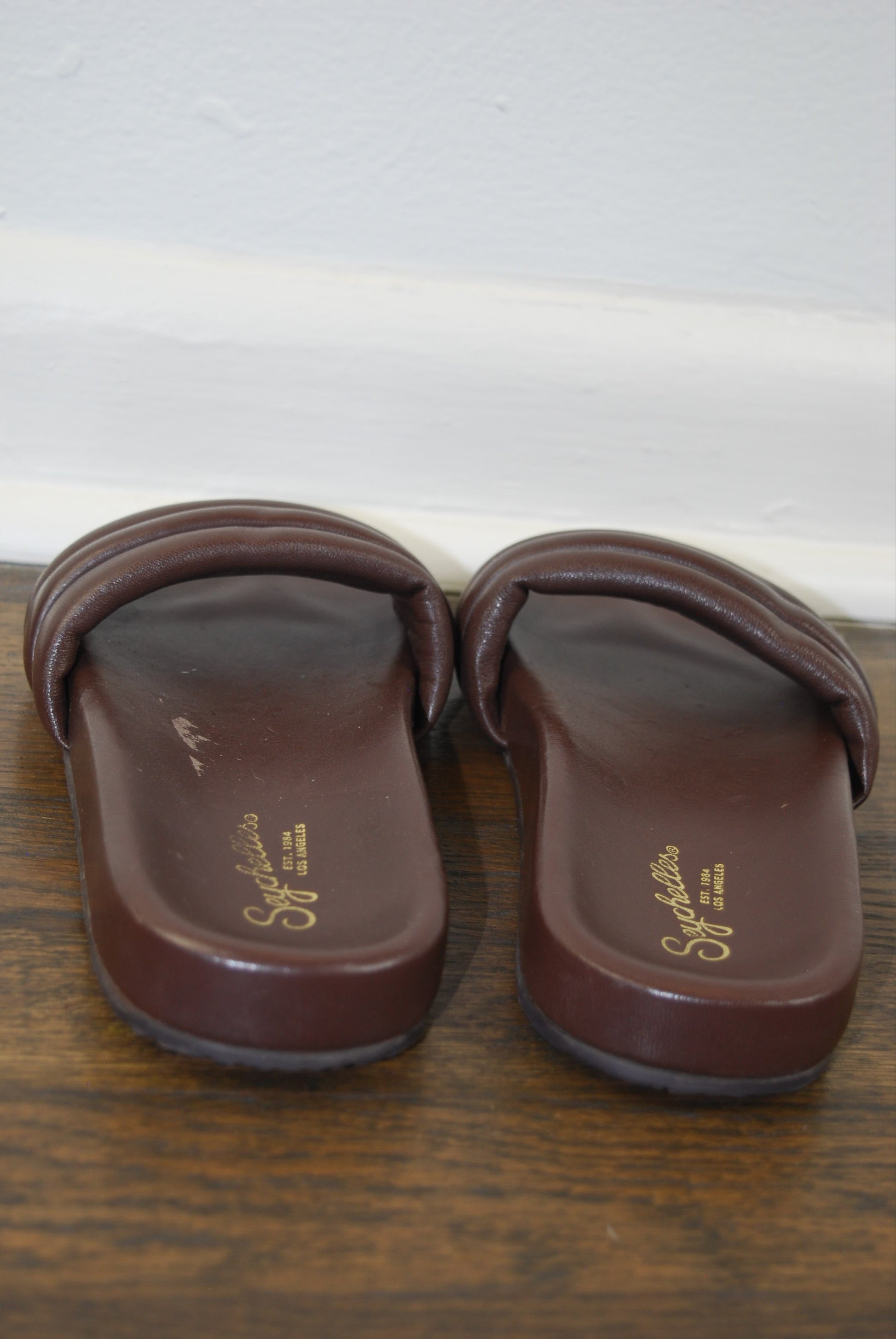 Pair of brown slipper boots with Seychelle branding on a wooden surface.