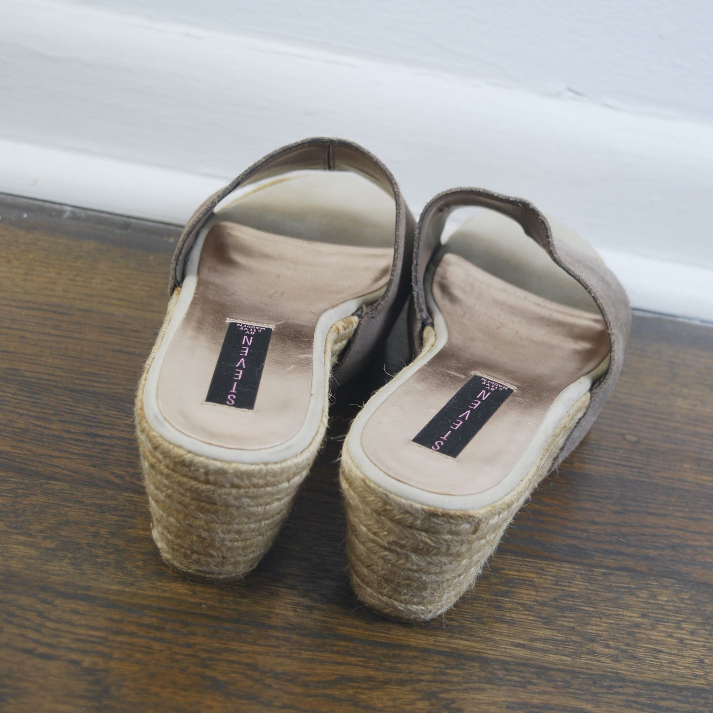 Pair of brown sandals with wedge soles on a wooden floor.