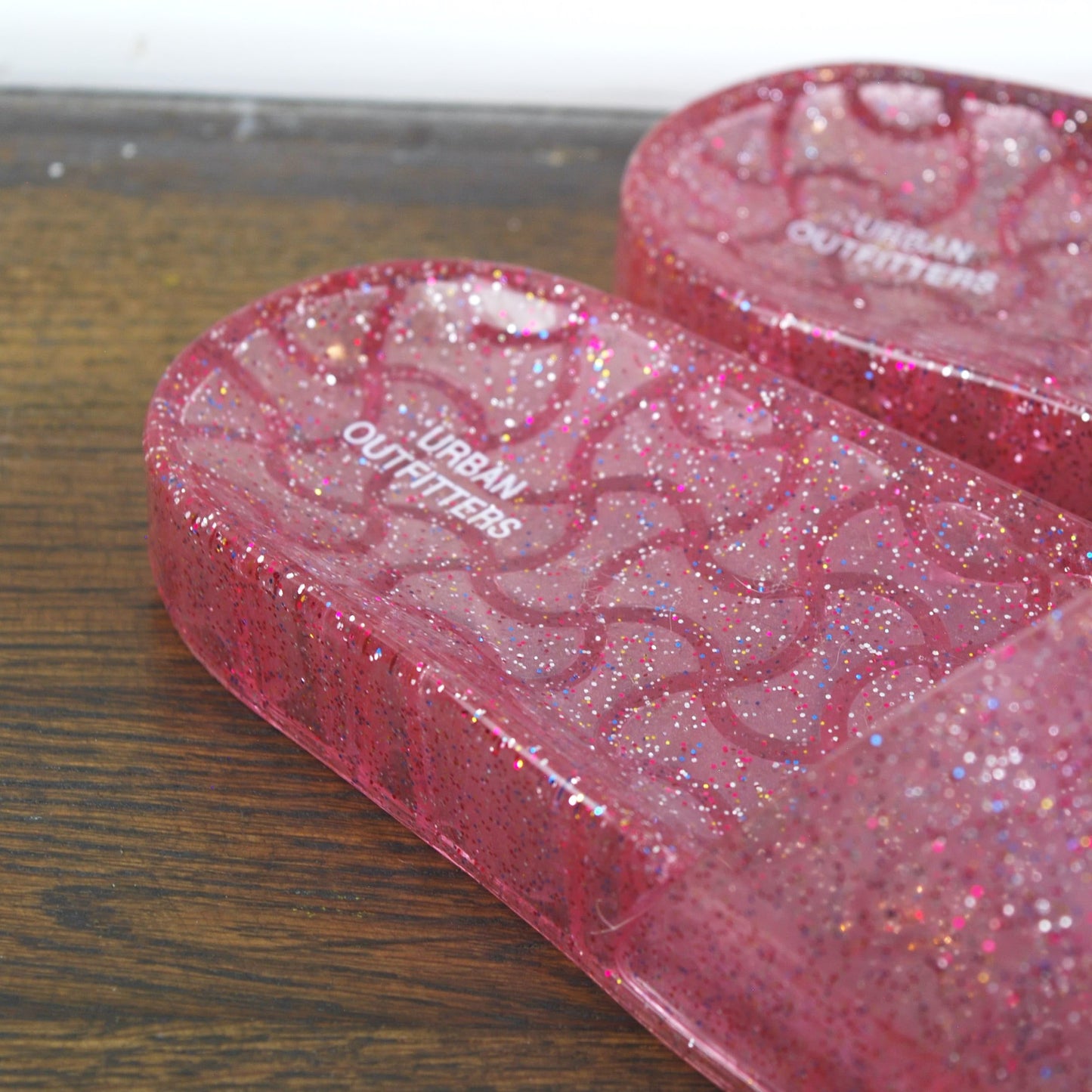Pink glittery case with 'Curren Cufflinks' branding on a wooden surface.