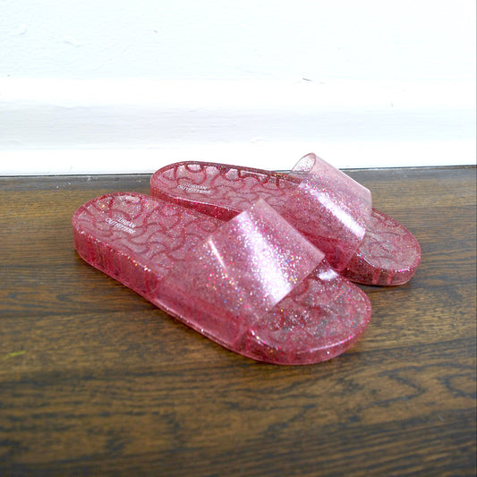 Pink flip-flops on a wooden surface with a white background