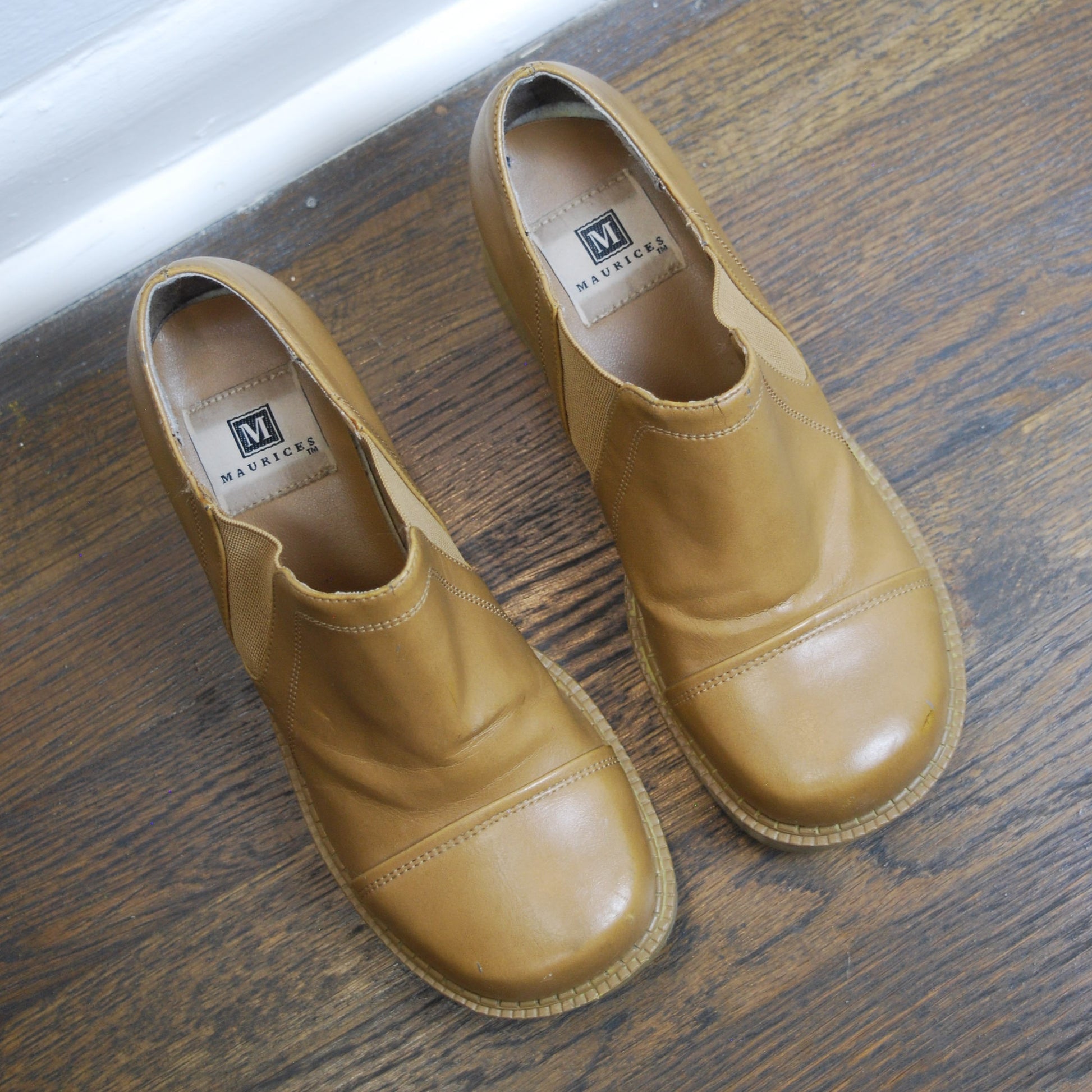 Pair of tan leather shoes on a wooden floor