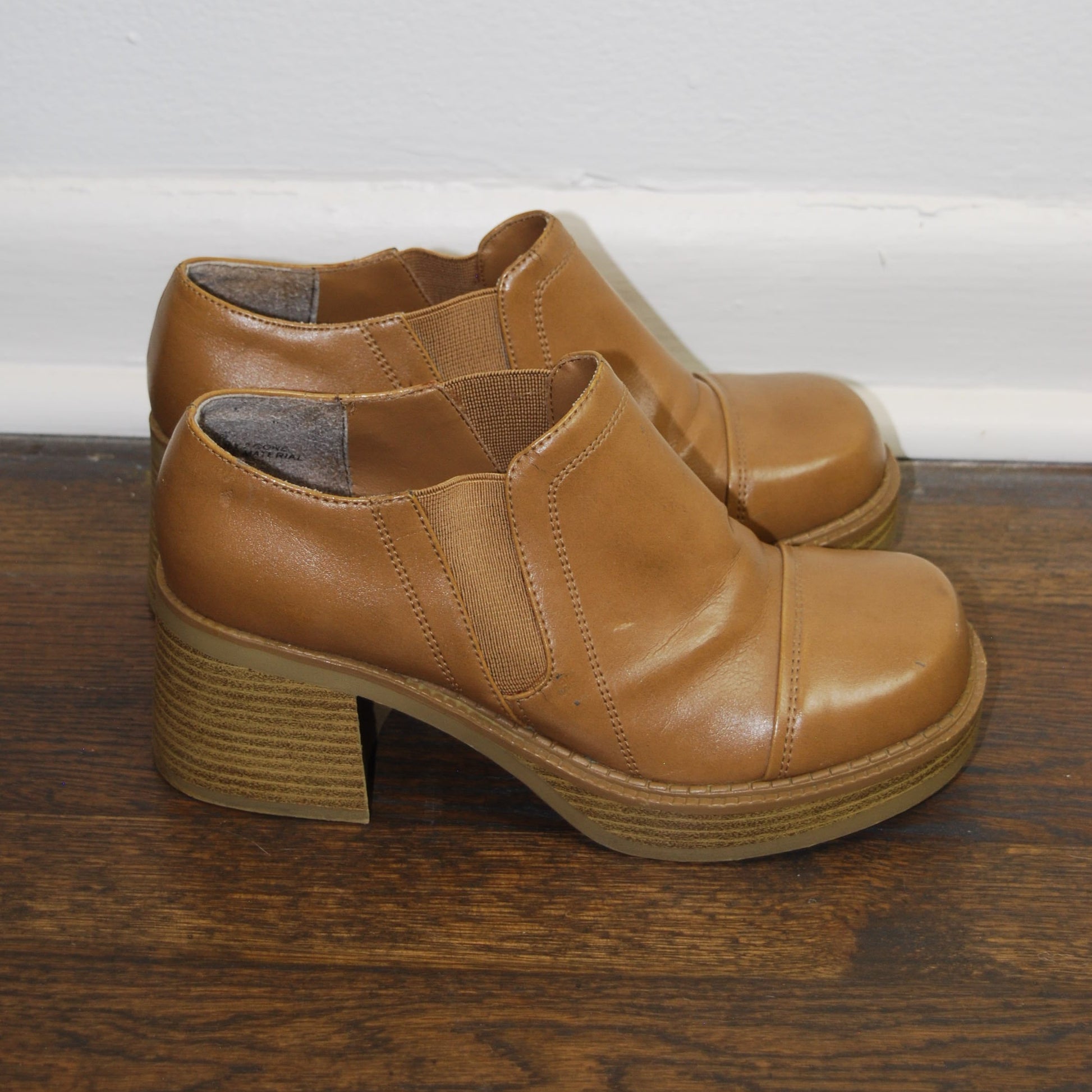 Pair of brown leather shoes on a wooden floor.