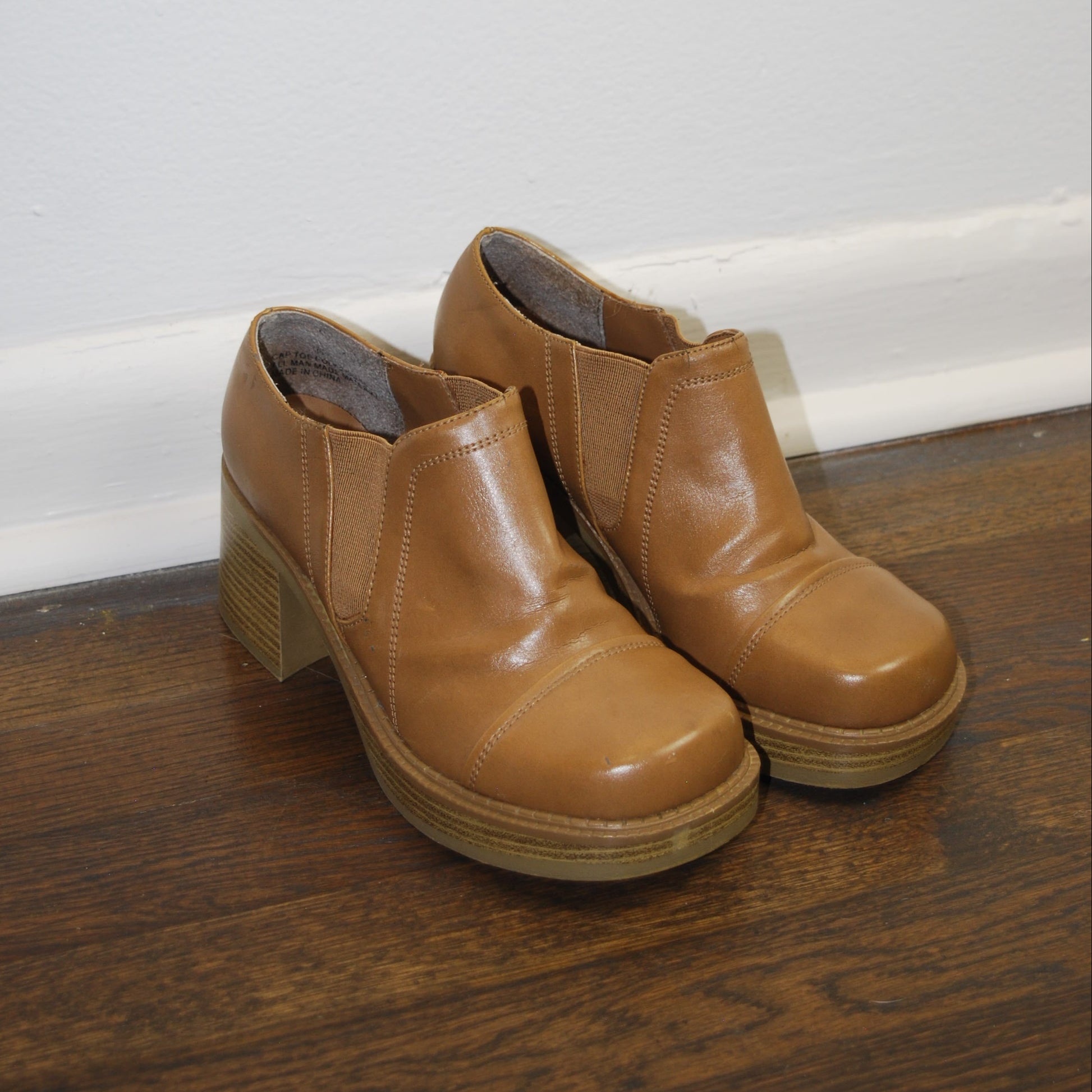 Pair of brown leather boots on a wooden floor.