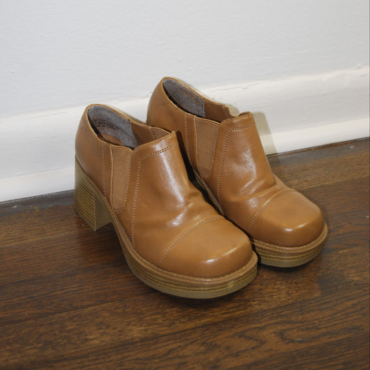 Pair of brown leather boots on a wooden floor.