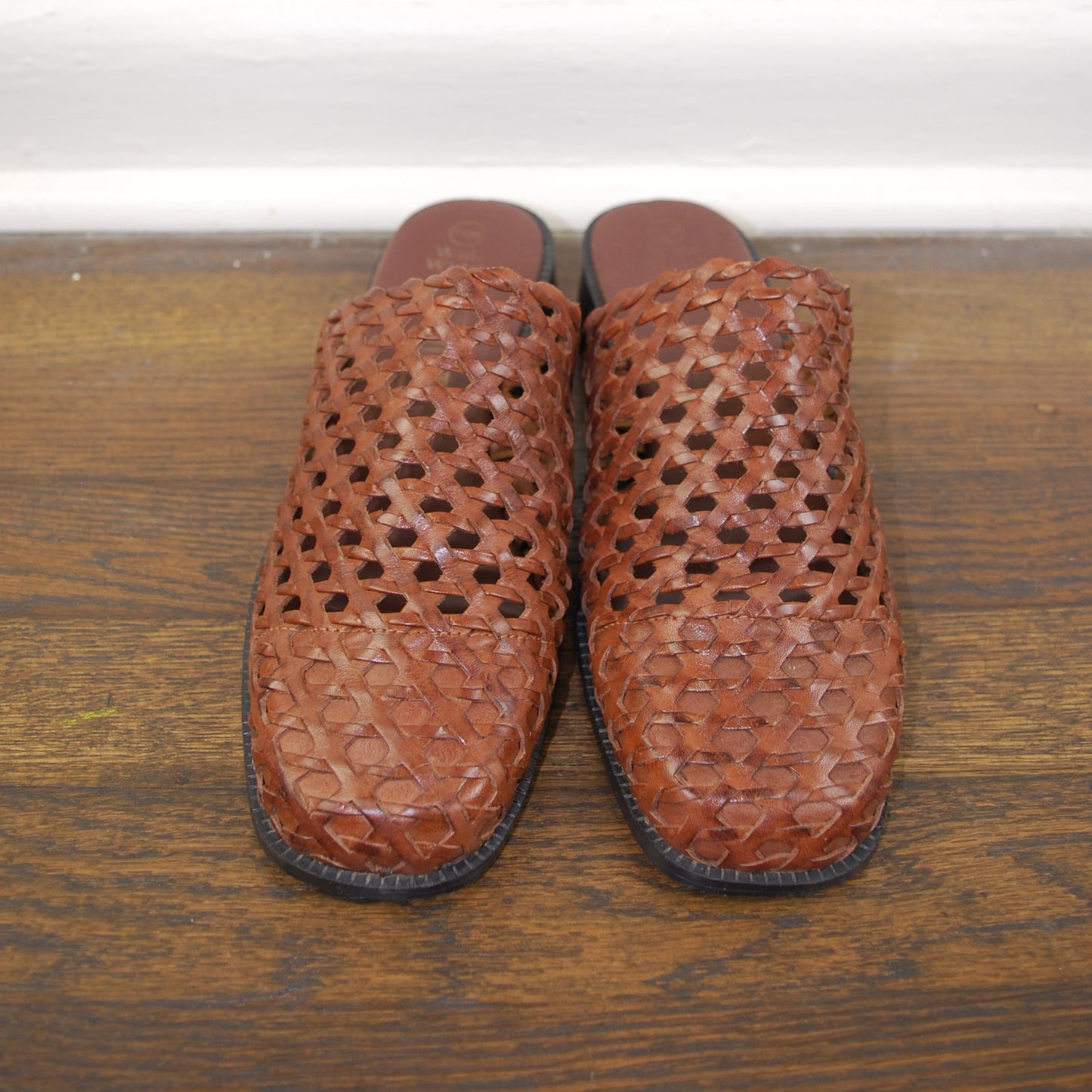 Pair of brown slippers on a wooden floor.