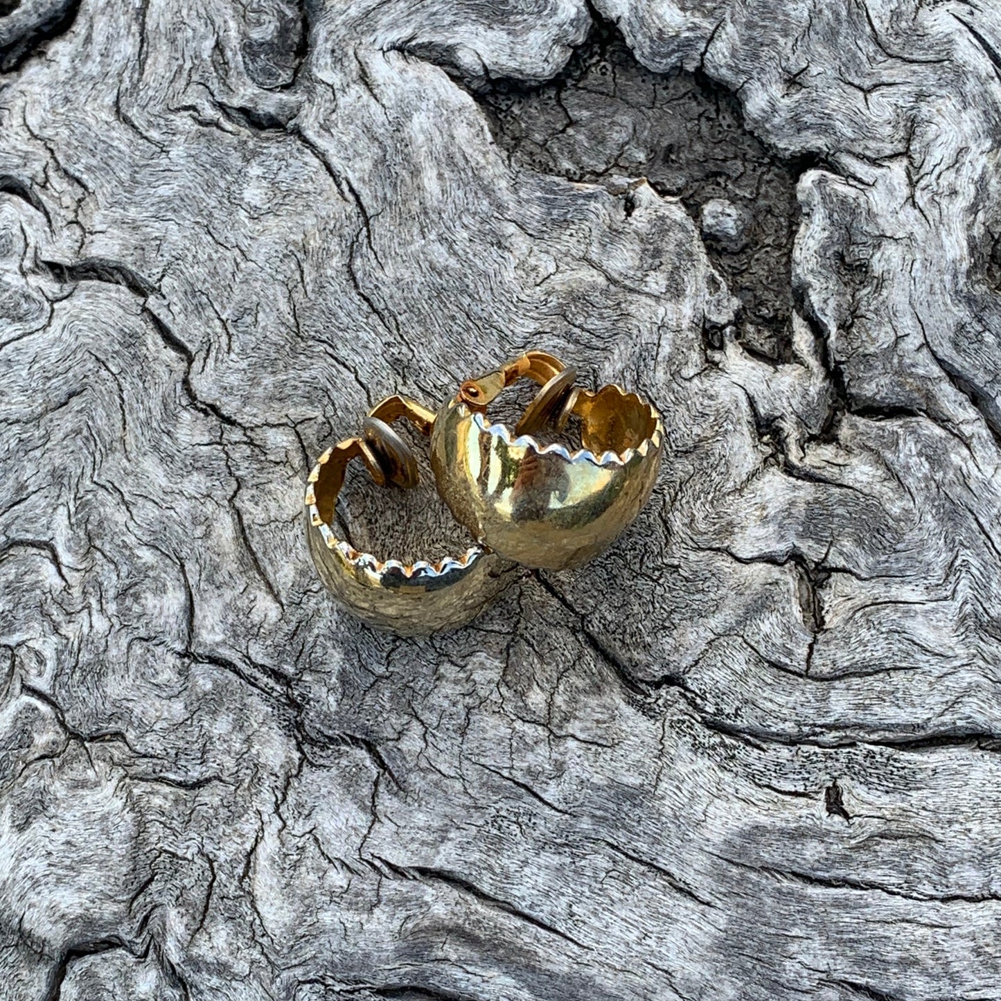 Gold earring on a textured gray surface