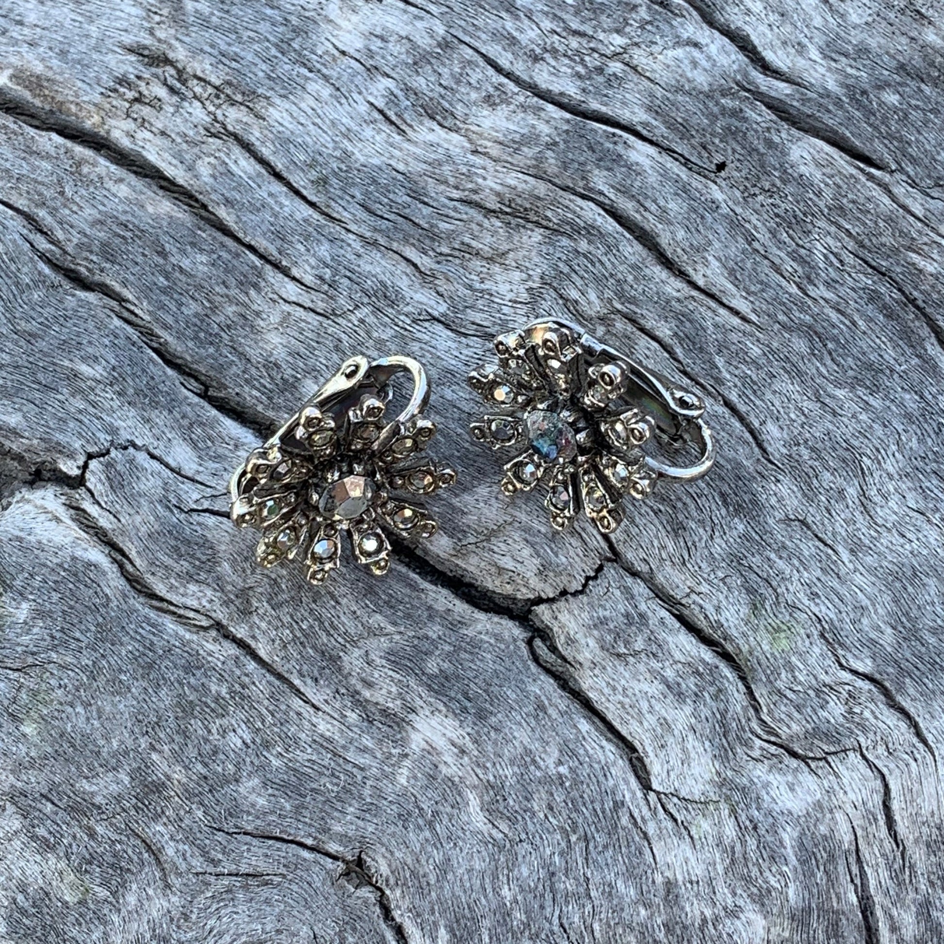 Pair of silver earrings on a textured stone surface
