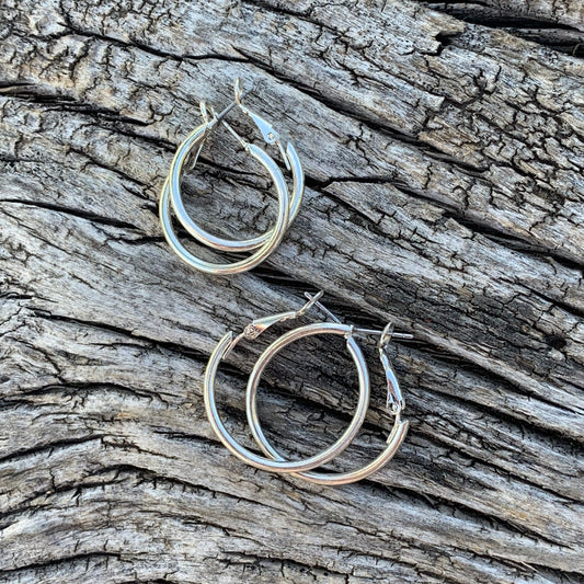 Silver hoop earrings on a textured wooden surface