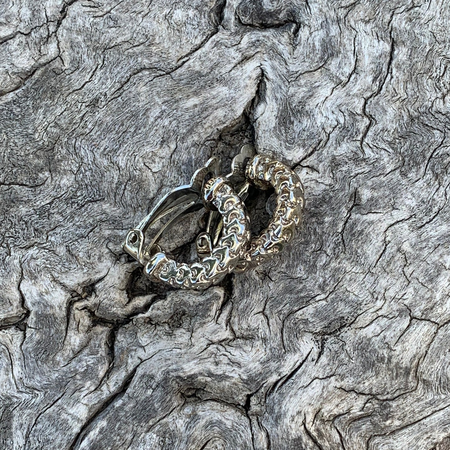 Silver ring with intricate design embedded in a textured stone surface
